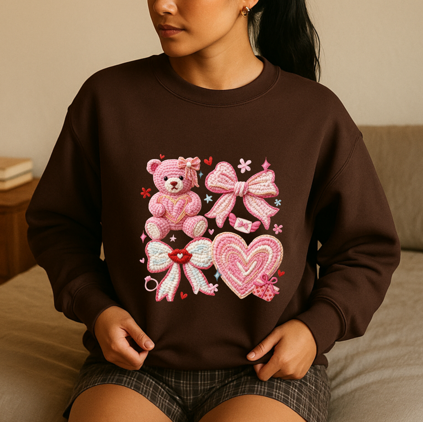 Person wearing a brown sweatshirt with decorative elements including a teddy bear, hearts, and bows.
