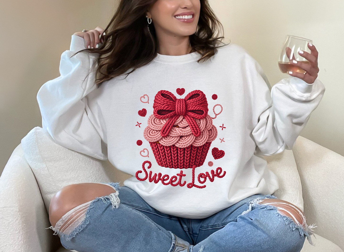Person wearing a white sweatshirt with a red cupcake design and 'Sweet Love' text, sitting on a white couch.