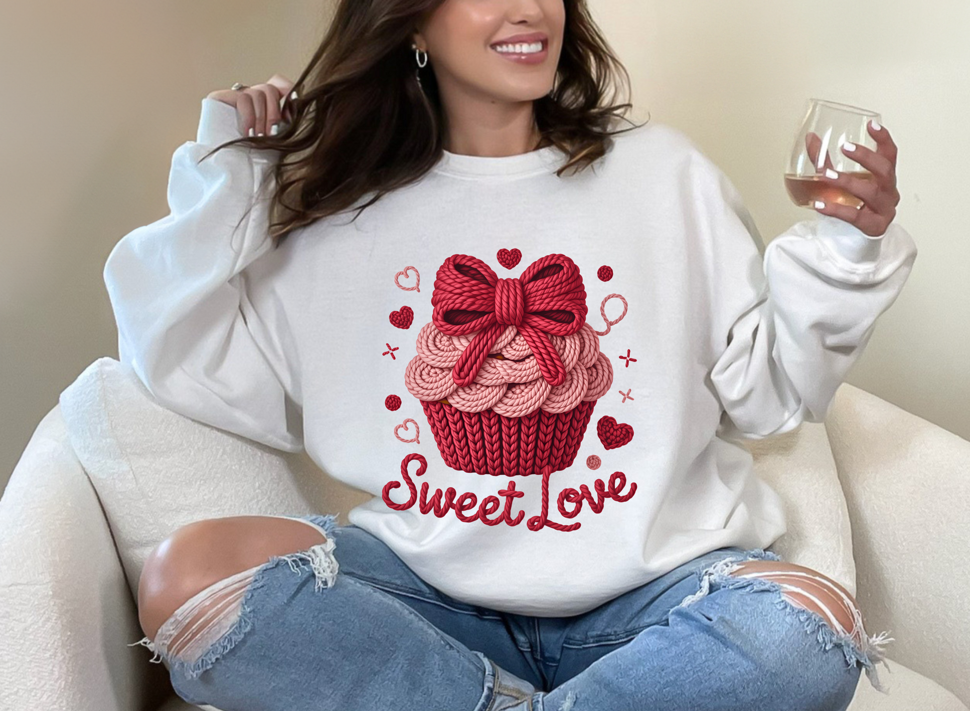 Person wearing a white sweatshirt with a red cupcake design and 'Sweet Love' text, sitting on a white couch.